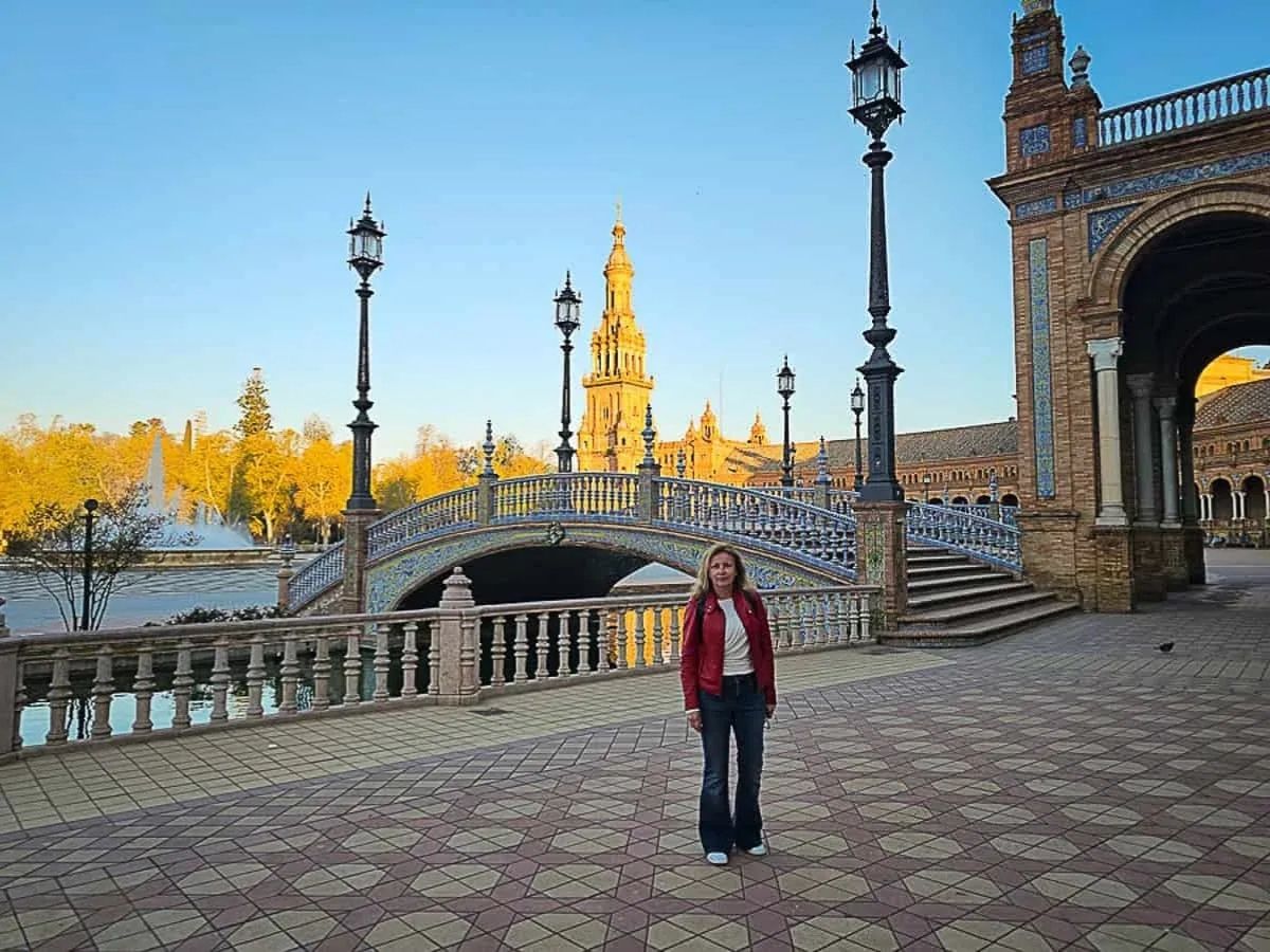 Златна изгревна светлина над моста и кулата на Пласа де Еспаня в Севиля.